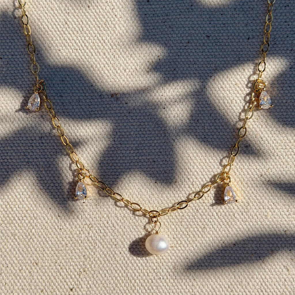Gold necklace with pearls on a textured fabric background