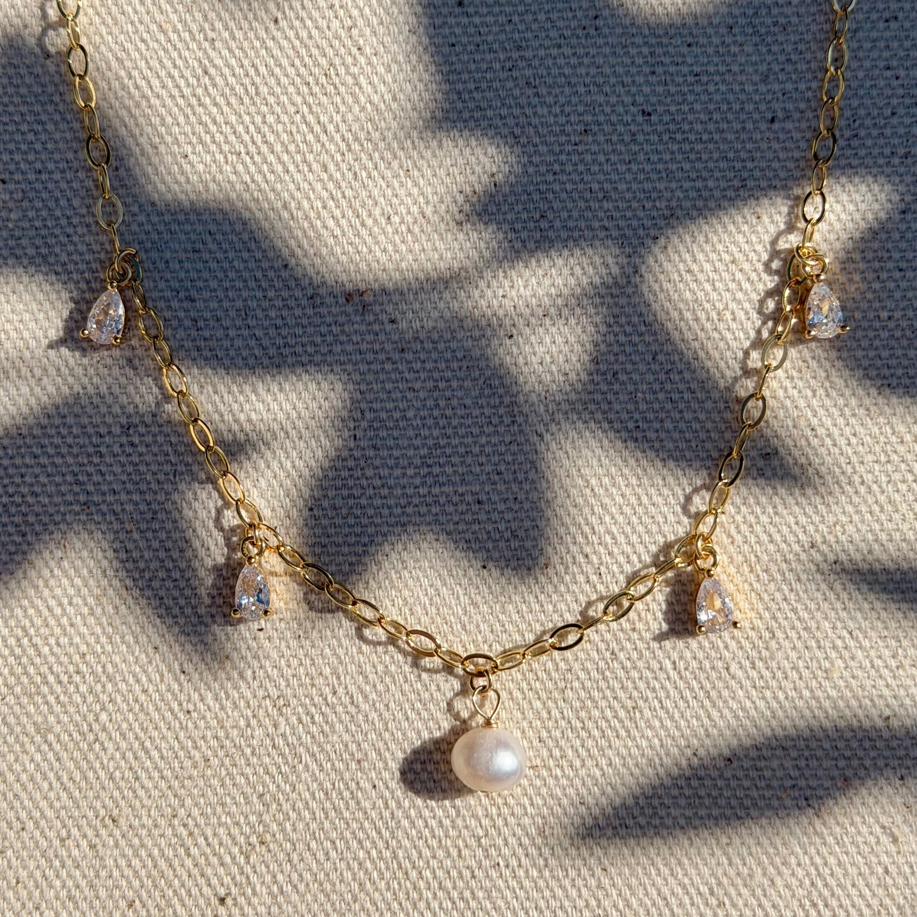 Gold necklace with pearls on a textured fabric background