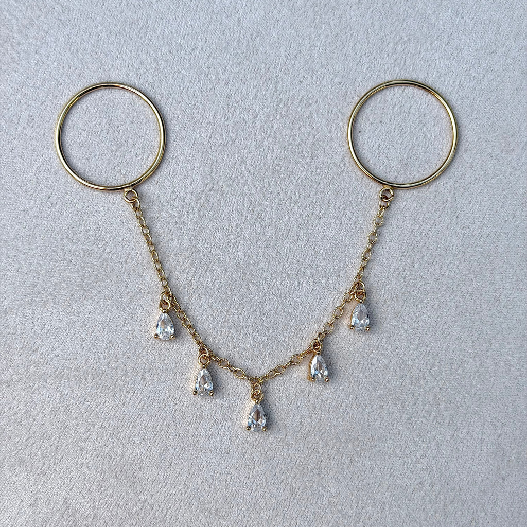 Gold keychain with hanging teardrop-shaped pendants on a light gray background