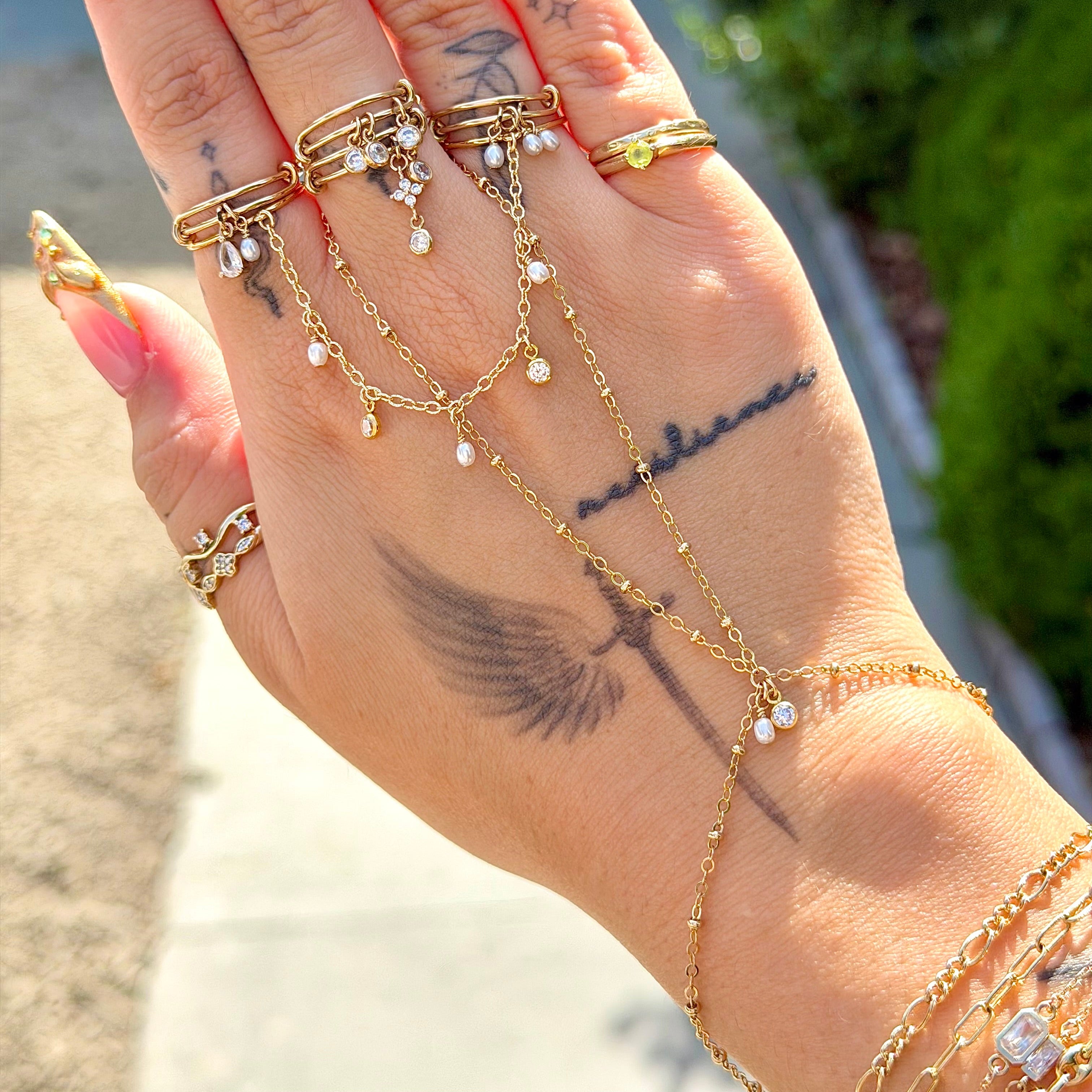 Hand wearing multiple gold rings with a blurred outdoor background