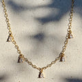 Gold necklace with small pendants on a textured white surface