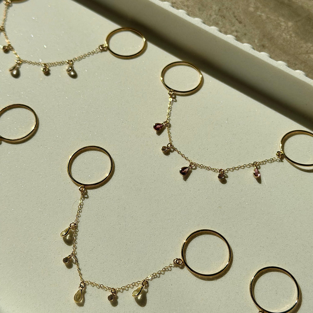 Gold necklaces with circular pendants on a white surface