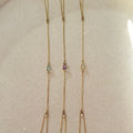 Long necklace with multiple gemstone pendants on a neutral background