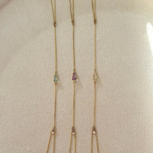 Long necklace with multiple gemstone pendants on a neutral background