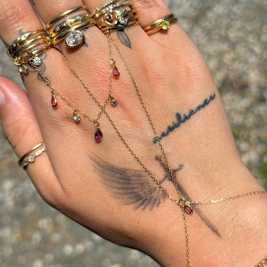 Hand with multiple gold rings and a bracelet on a textured surface