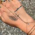 Hand with tattoos and gold jewelry on a textured surface