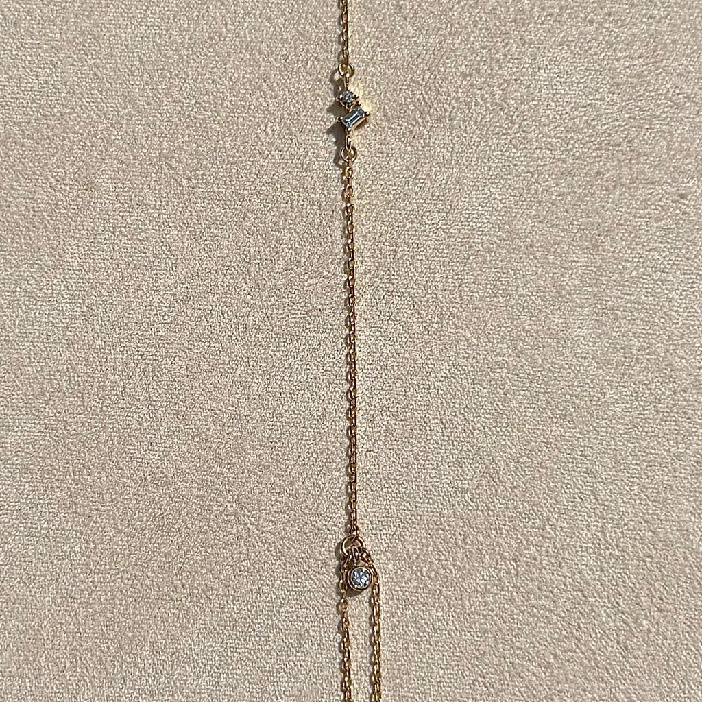 Delicate gold necklace on a textured beige surface