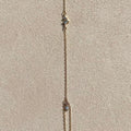 Delicate gold necklace on a textured beige surface