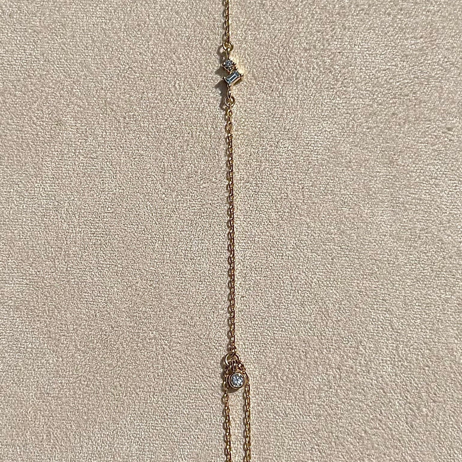 Delicate gold necklace on a textured beige surface