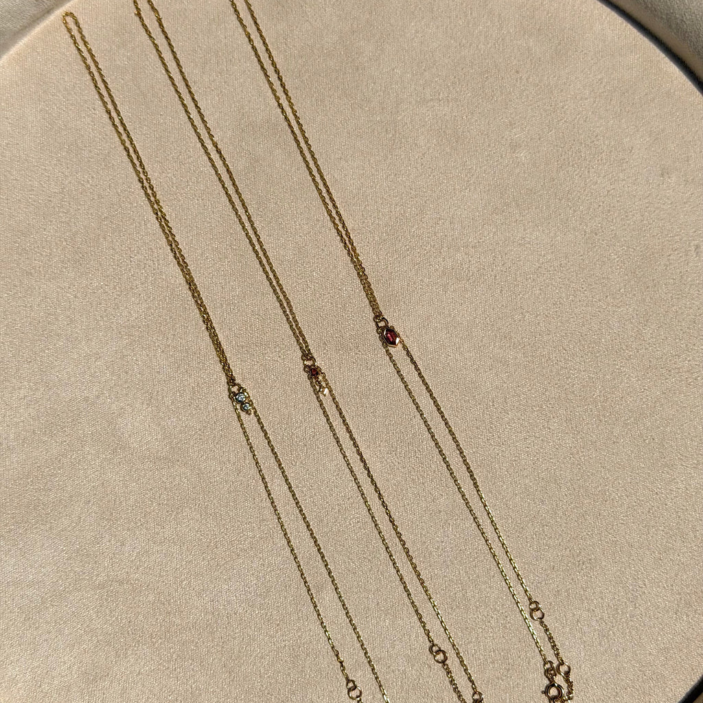 Three gold necklaces on a beige fabric background