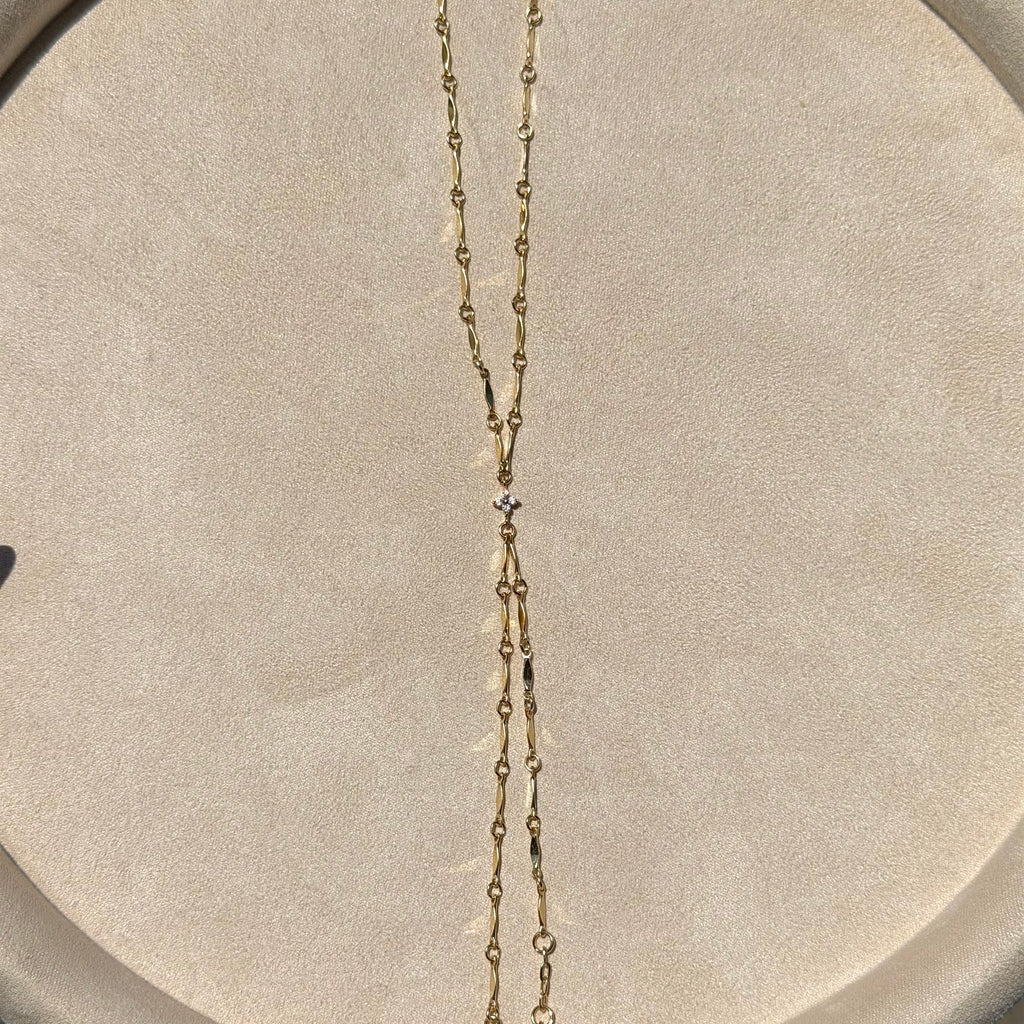Gold chain necklace on a gray cushioned surface