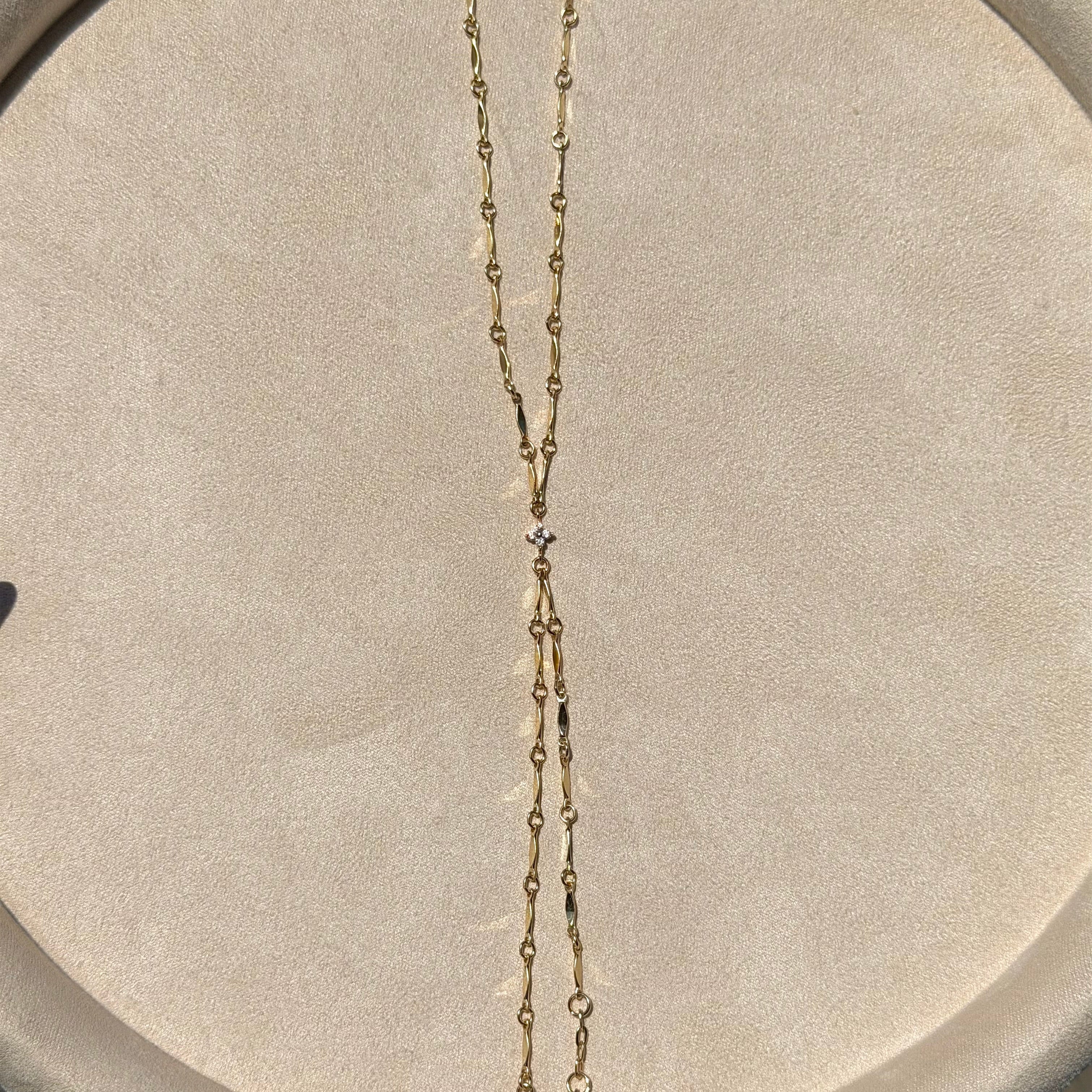 Gold chain necklace on a gray cushioned surface