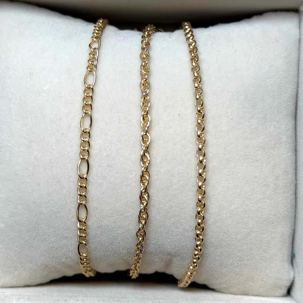 Gold and silver chain necklaces on a white cushioned surface
