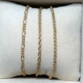 Gold and silver chain necklaces on a white cushioned surface