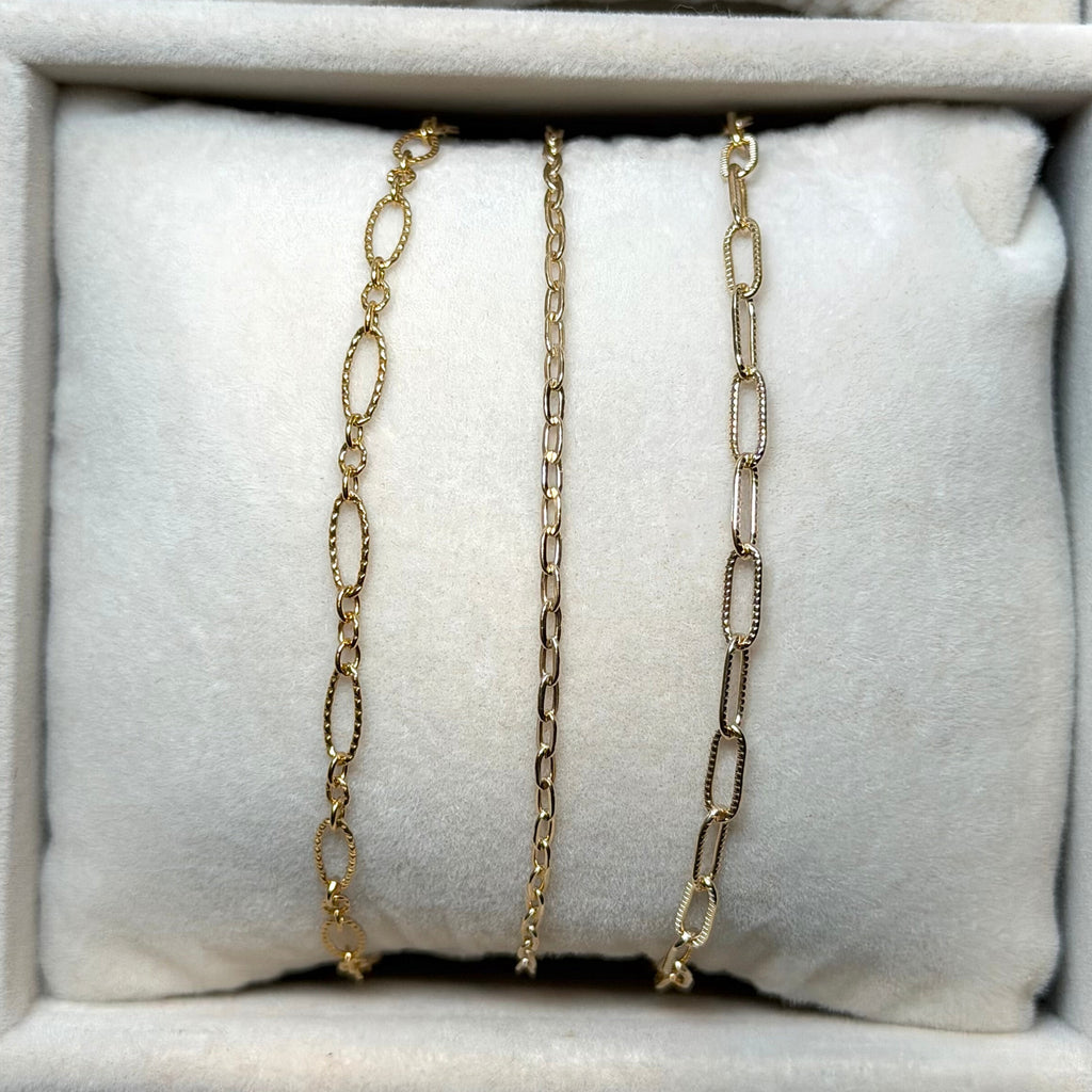 Gold chain necklaces on a white cushion in a jewelry box