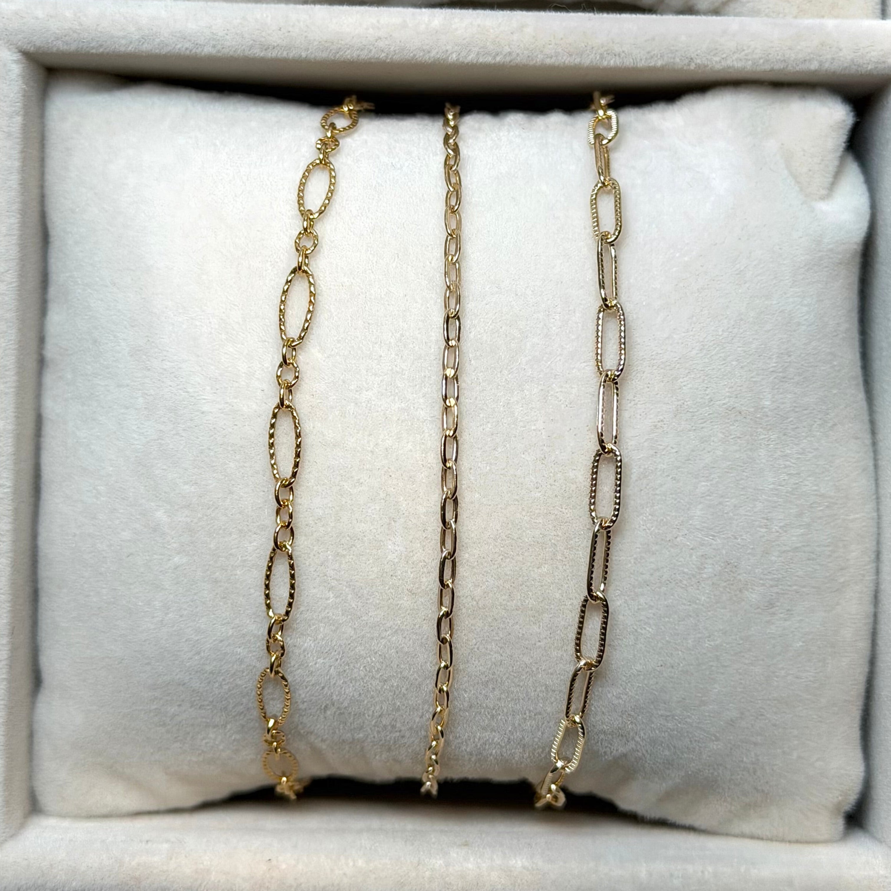 Gold chain necklaces on a white cushion in a jewelry box