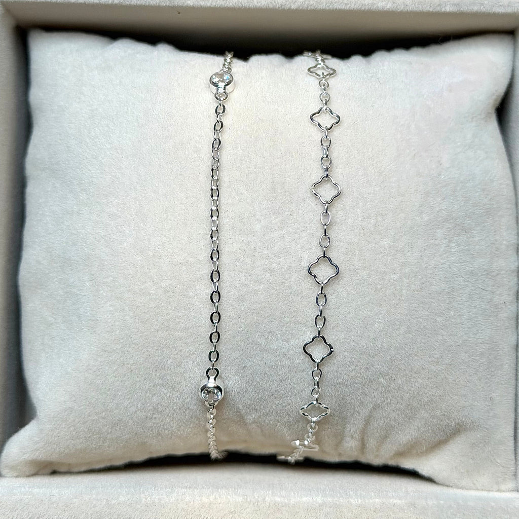 Silver chain necklace displayed on a cushioned surface with a neutral background