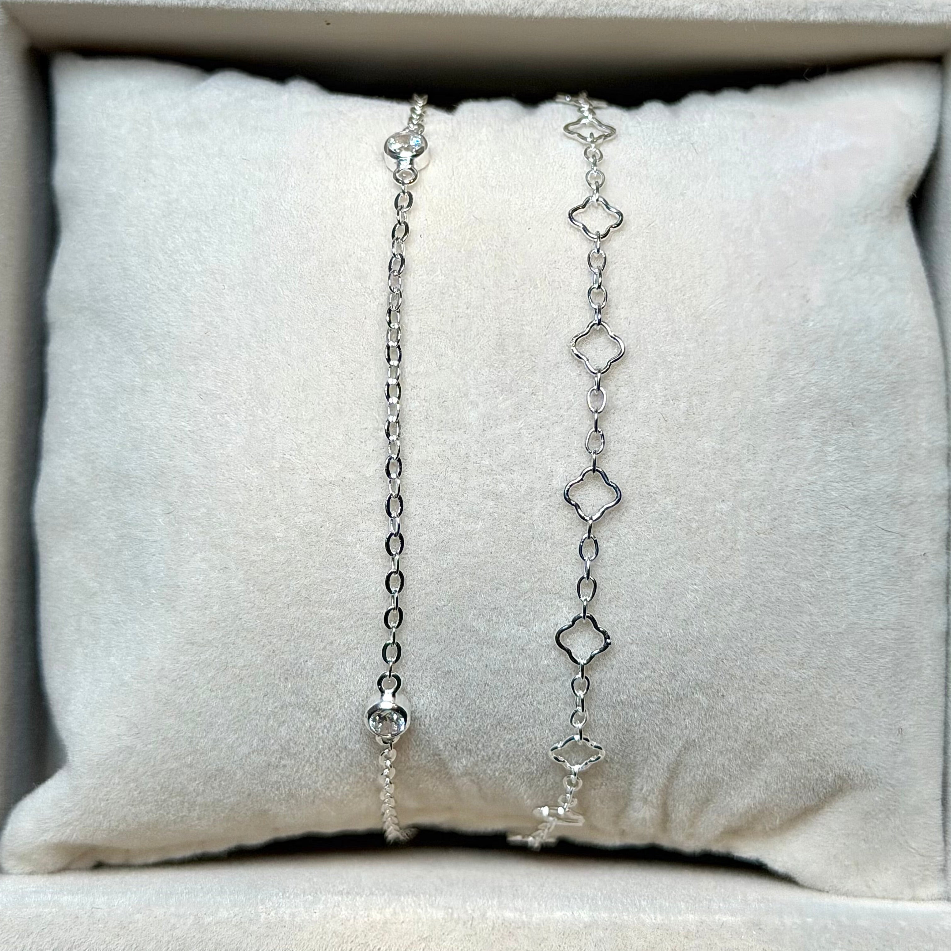 Silver chain necklace displayed on a cushioned surface with a neutral background