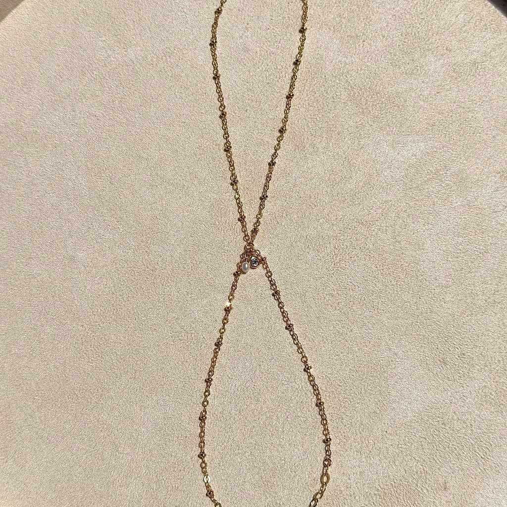 Gold chain necklace on a beige circular surface