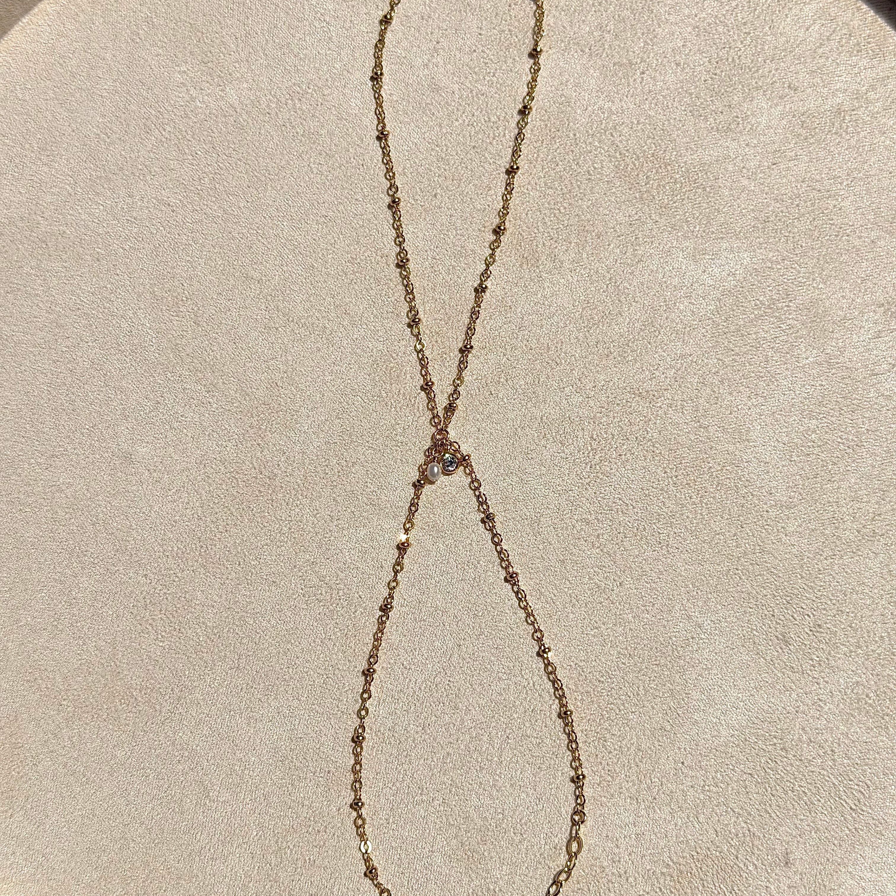 Gold chain necklace on a beige circular surface