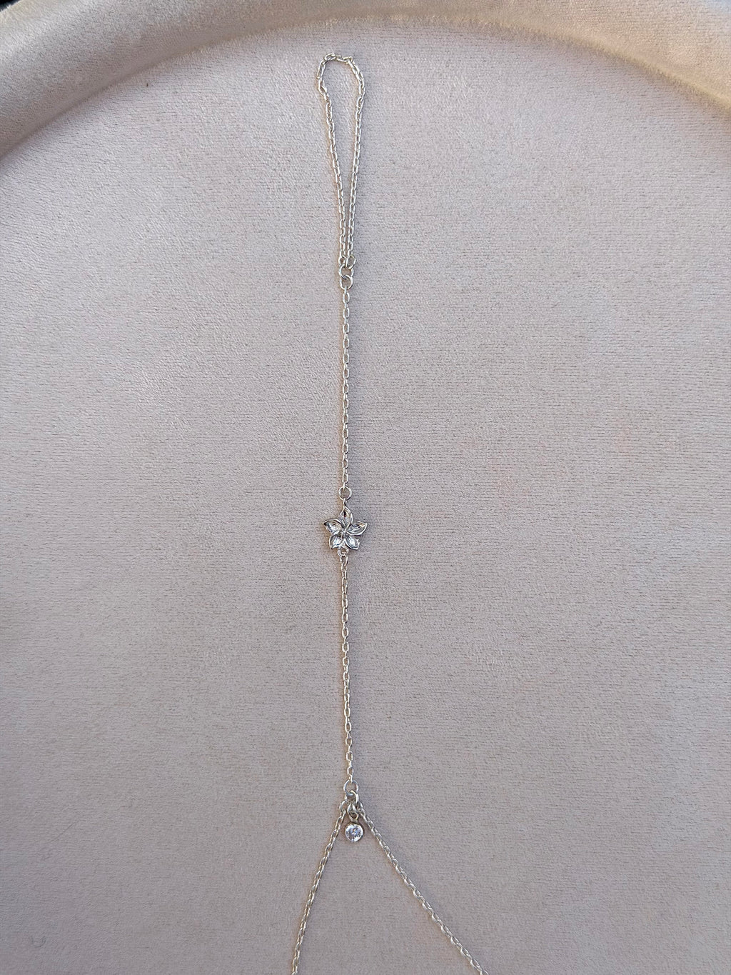 Delicate silver necklace with a flower pendant on a light gray surface