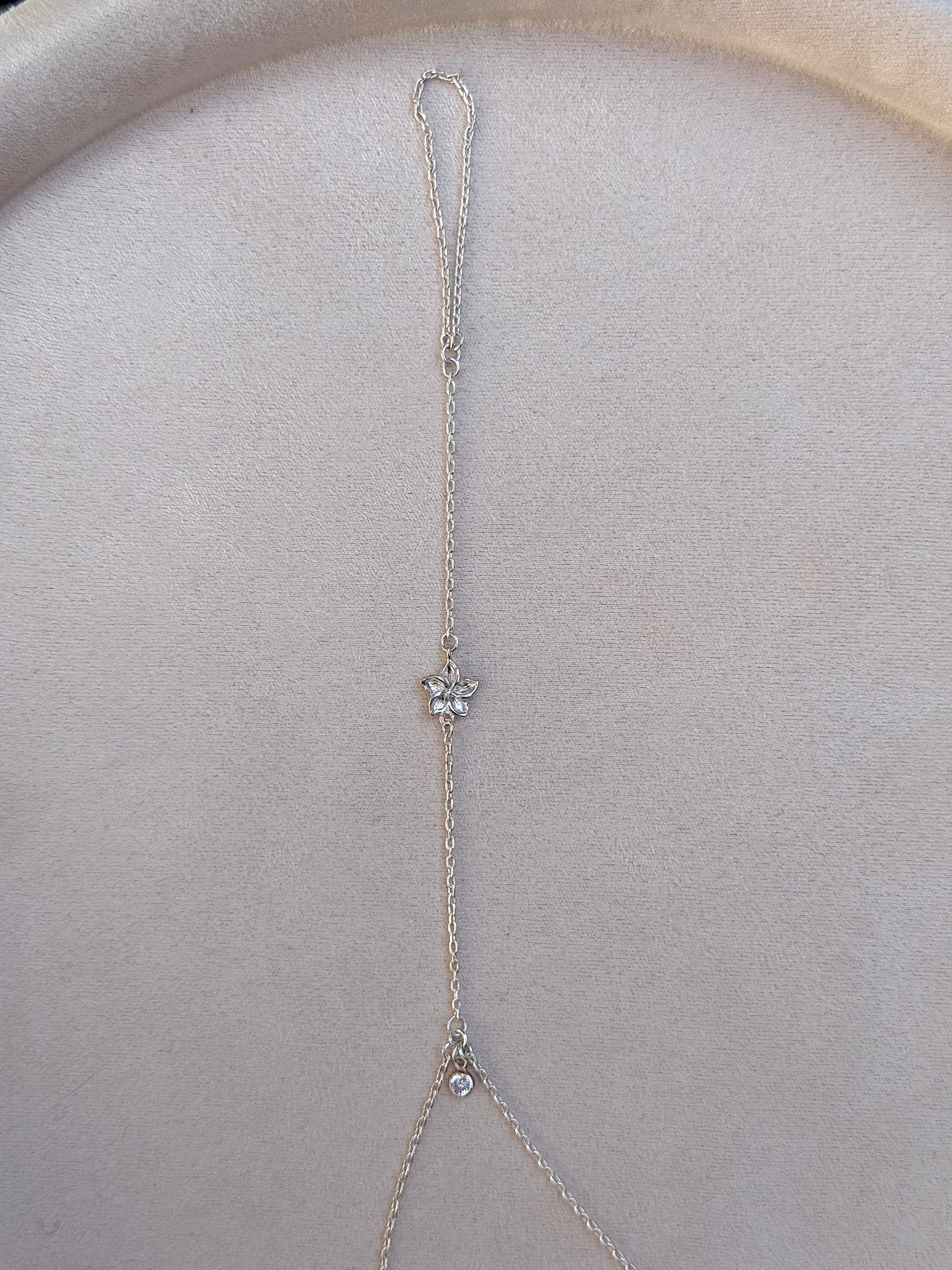 Delicate silver necklace with a flower pendant on a light gray surface