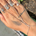 Hand wearing multiple silver rings with a blurred outdoor background