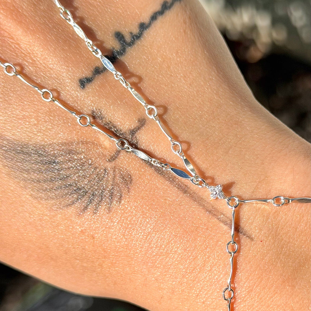 Silver chain bracelet on a wrist with tattoos and blurred background
