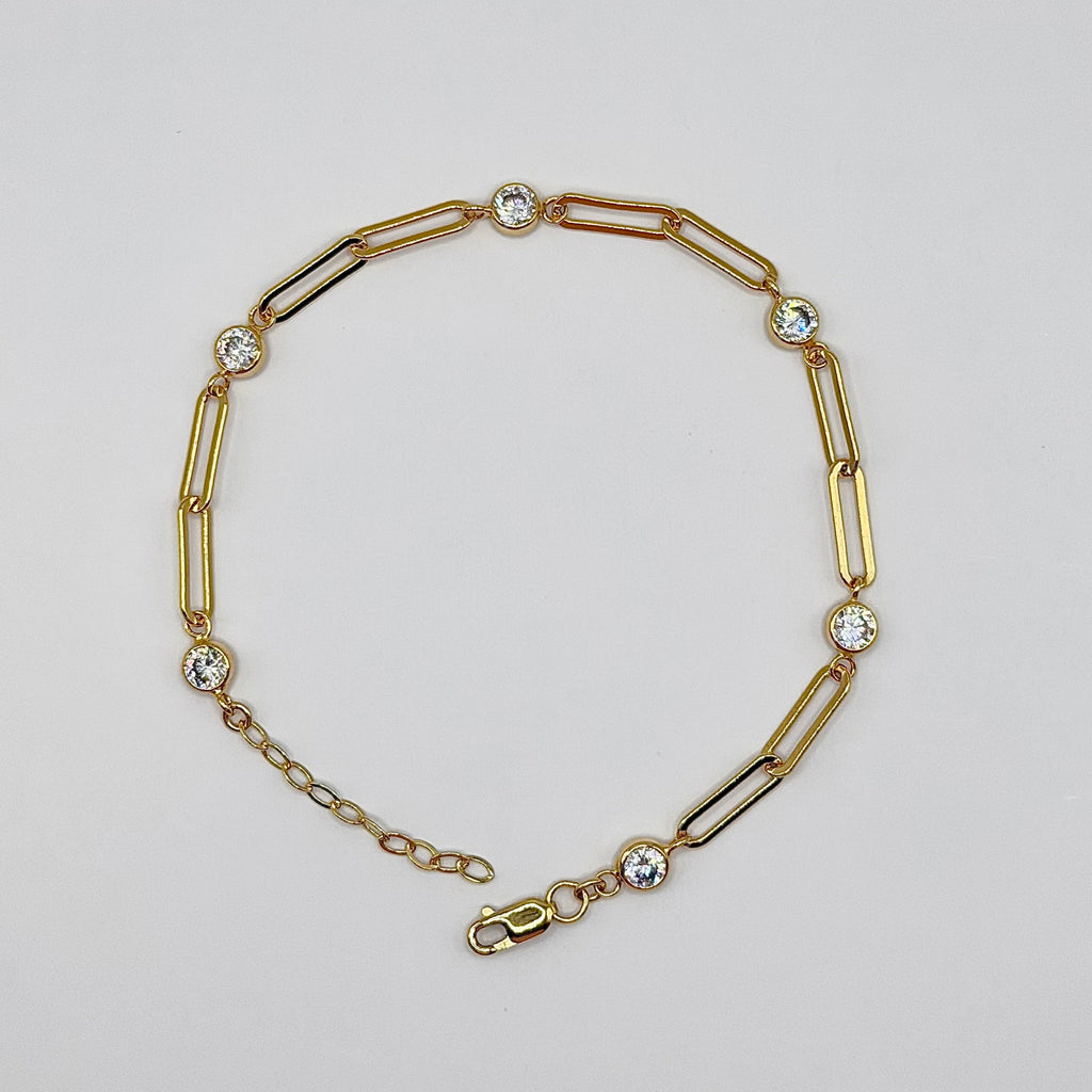 Gold bracelet with chain and bar links on a light gray background