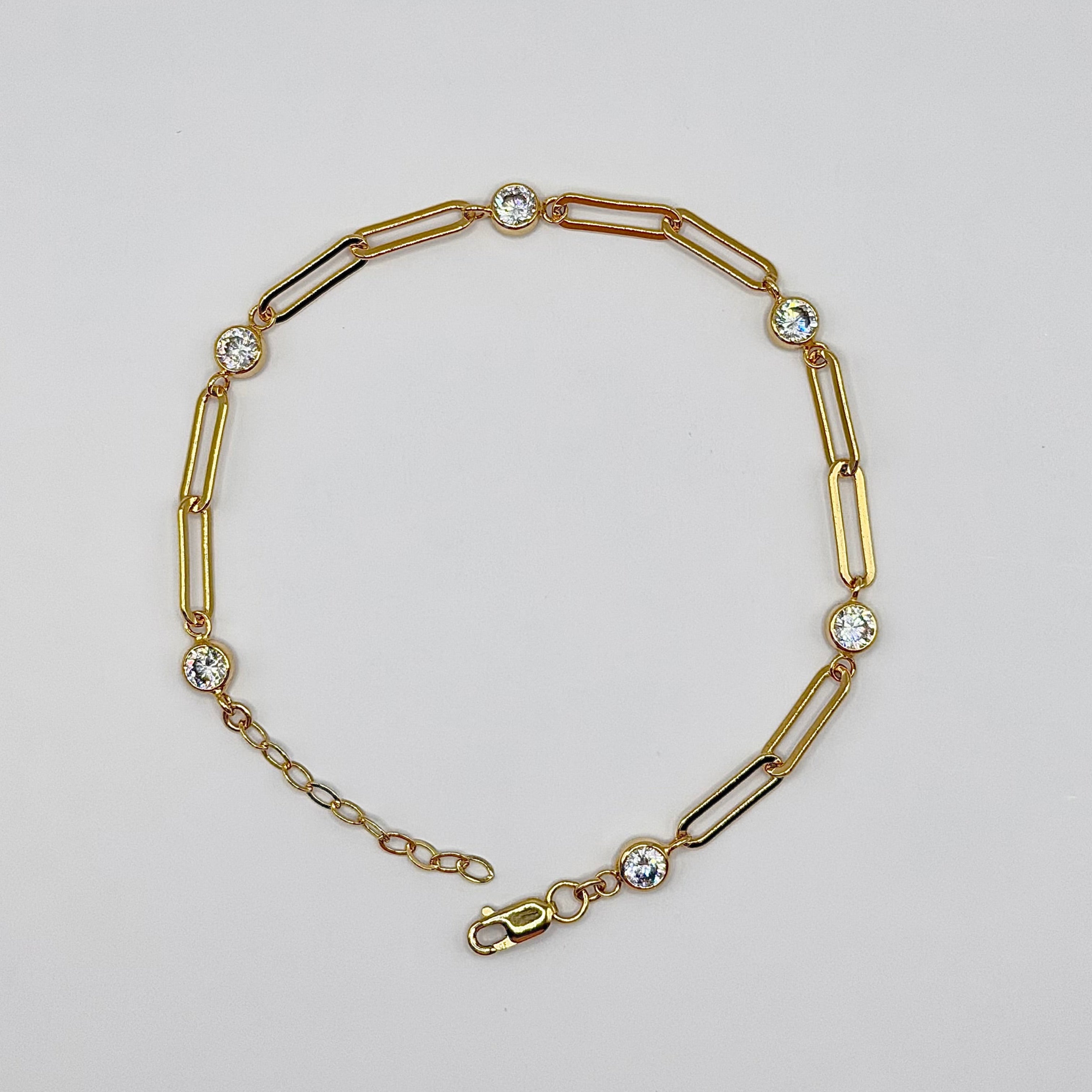 Gold bracelet with chain and bar links on a light gray background