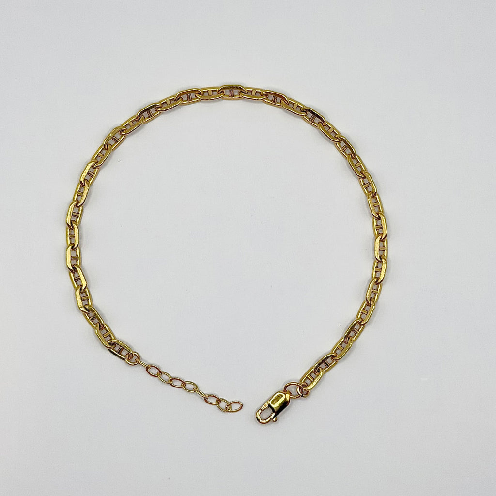 Gold chain bracelet on a light gray background
