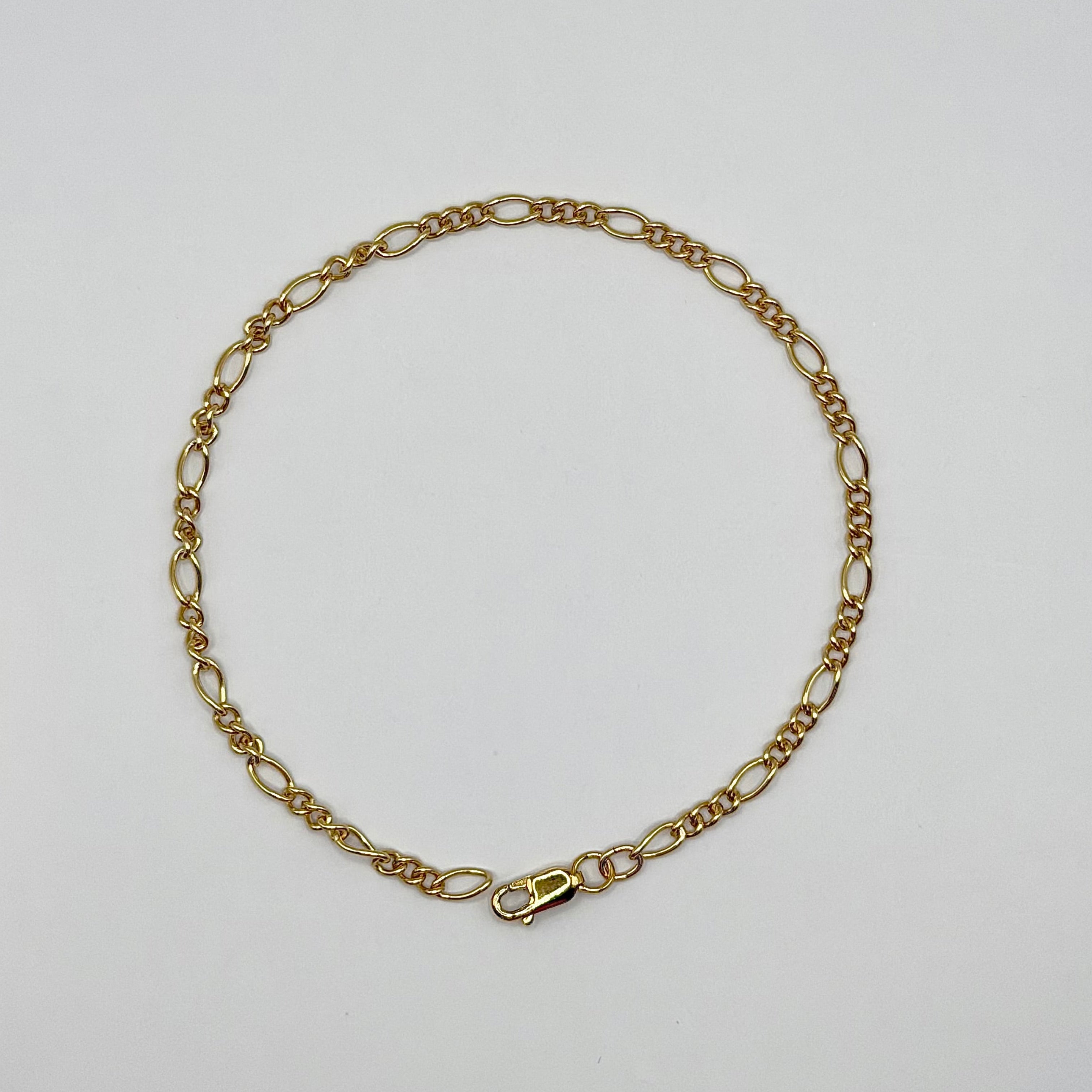 Gold chain bracelet on a light gray background