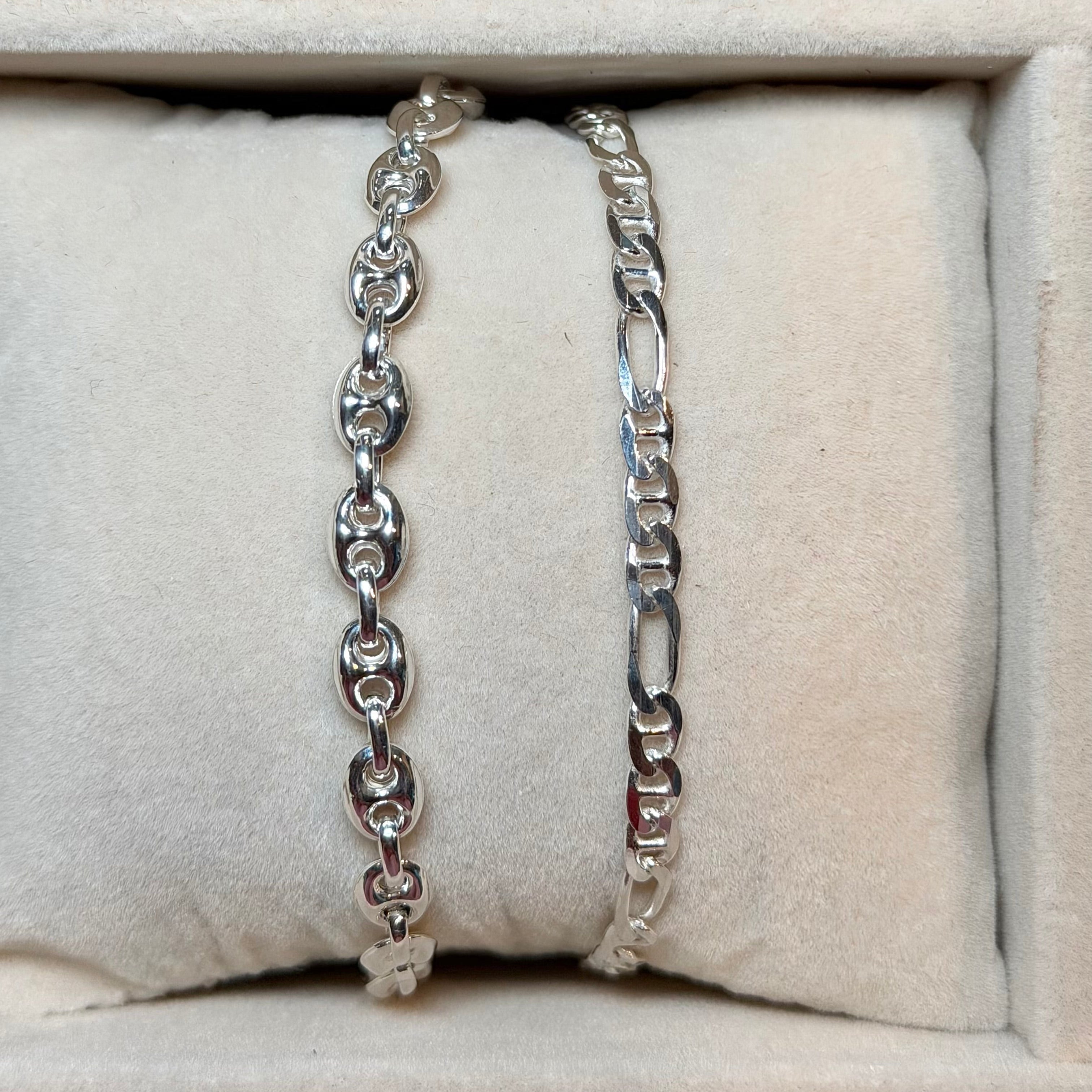 Two silver bracelets on a textured beige surface