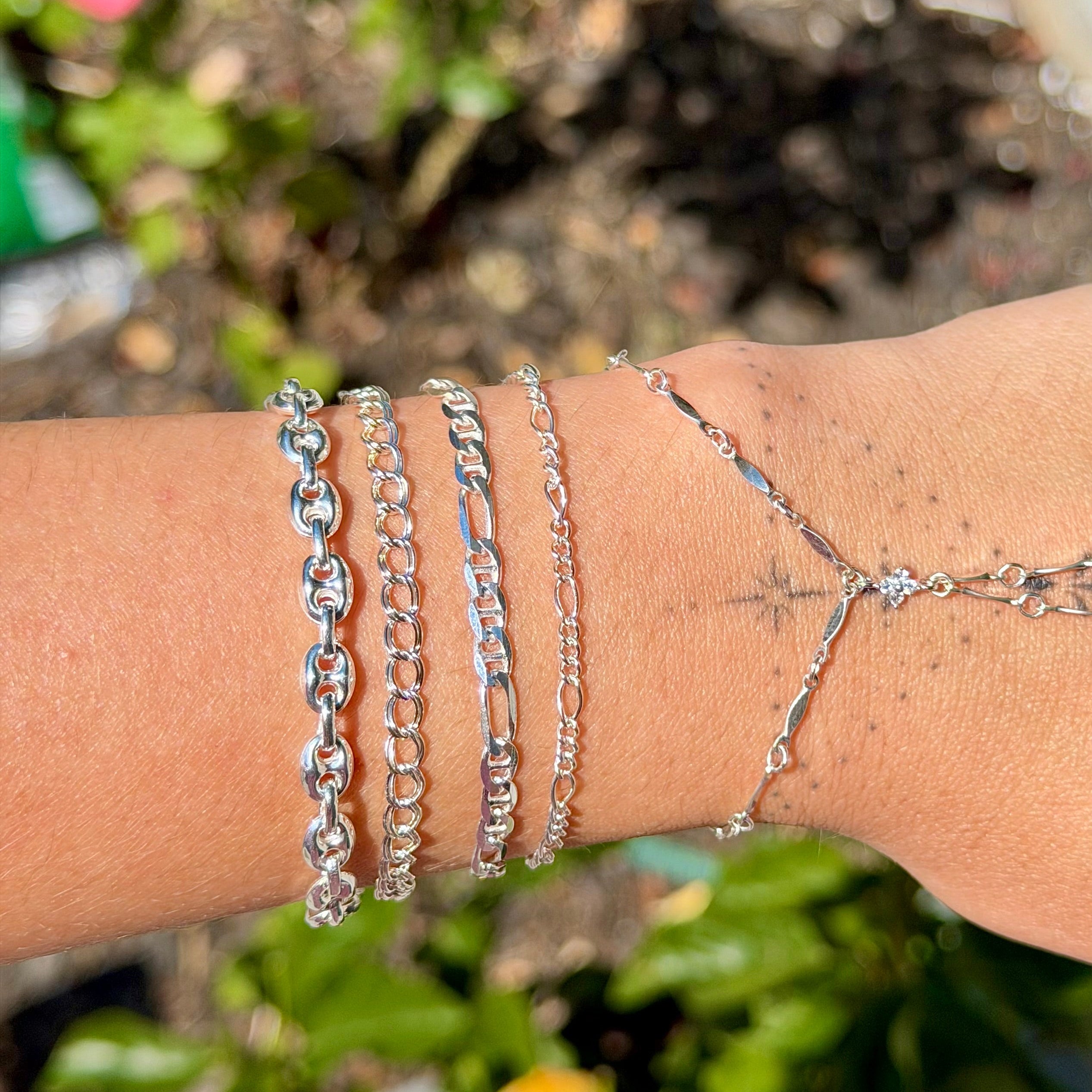Silver bracelets on a wrist with a blurred natural background