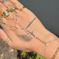Hand wearing multiple gold rings and bracelets with a blurred natural background
