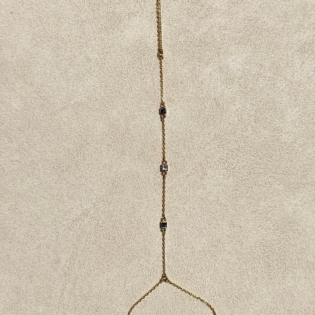 Gold necklace with small beads on a beige cushion