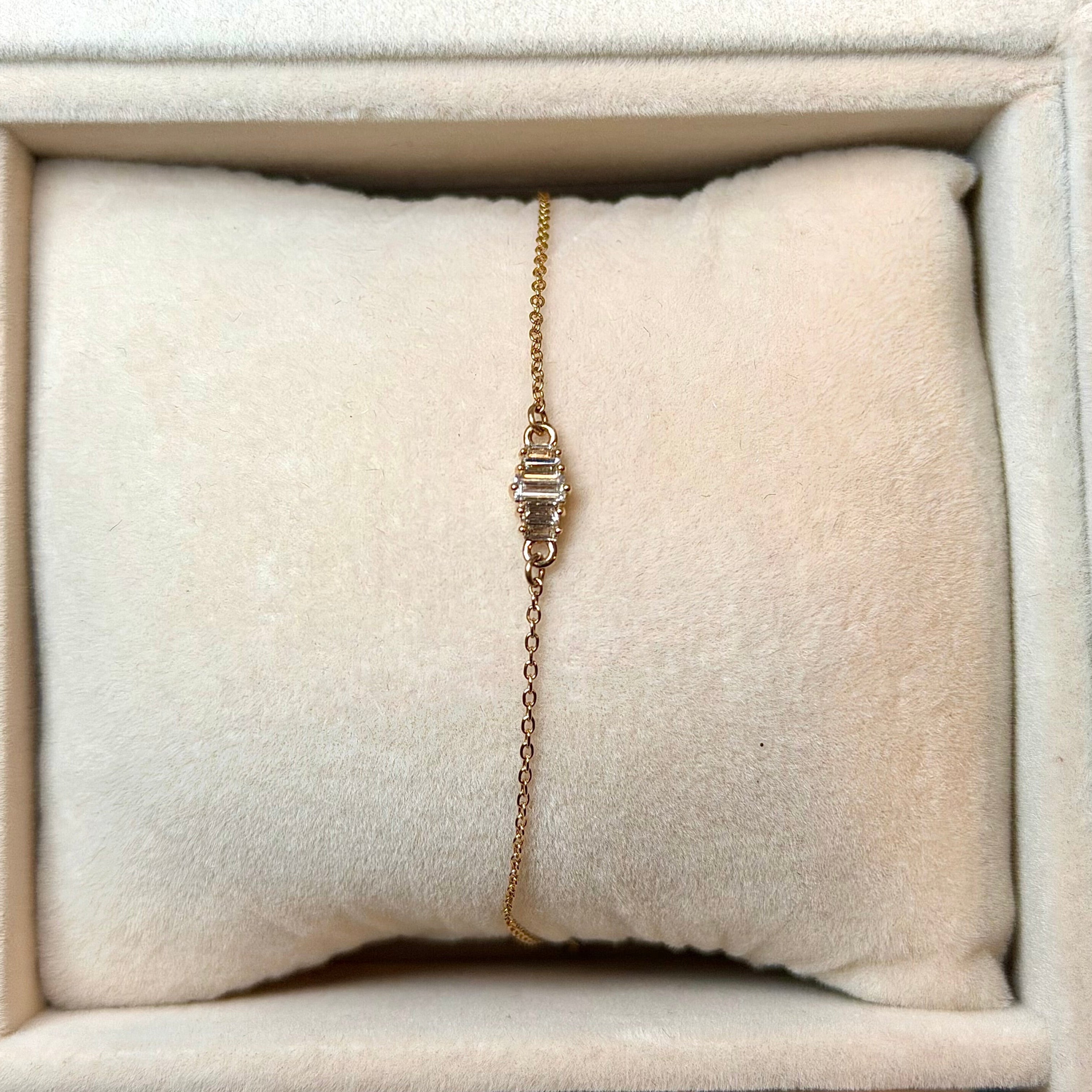Gold bracelet on a white cushion in a jewelry box
